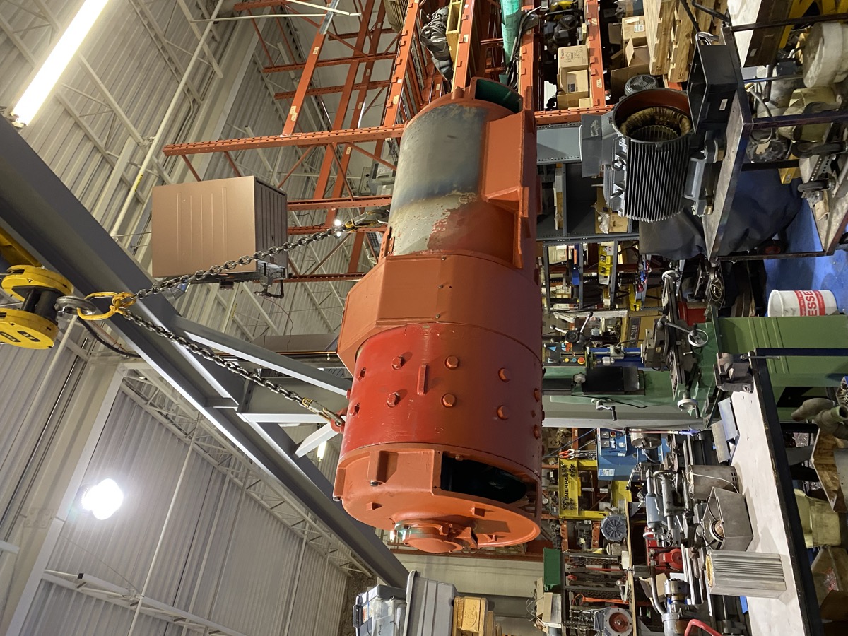 Massive orange industrial motor on shop floor with overhead crane at Complete Electric Calgary